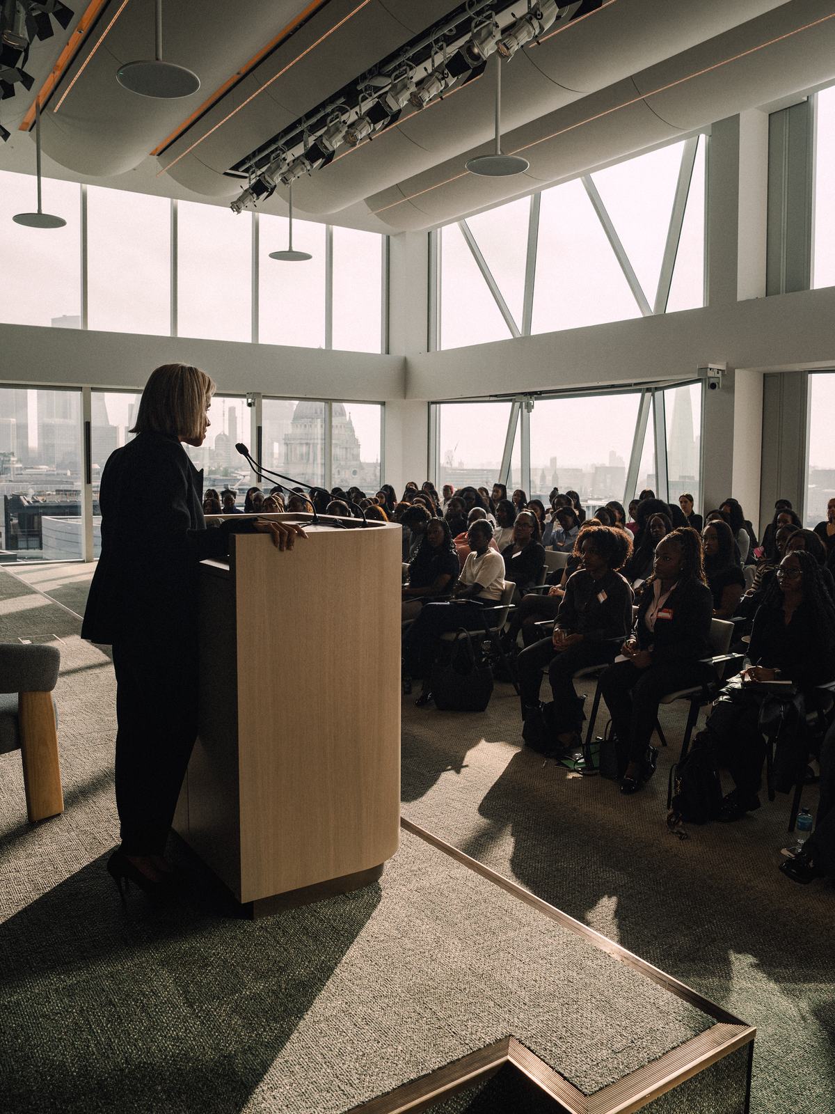 A speaker at the lectern addressing a full room at Travers Smith